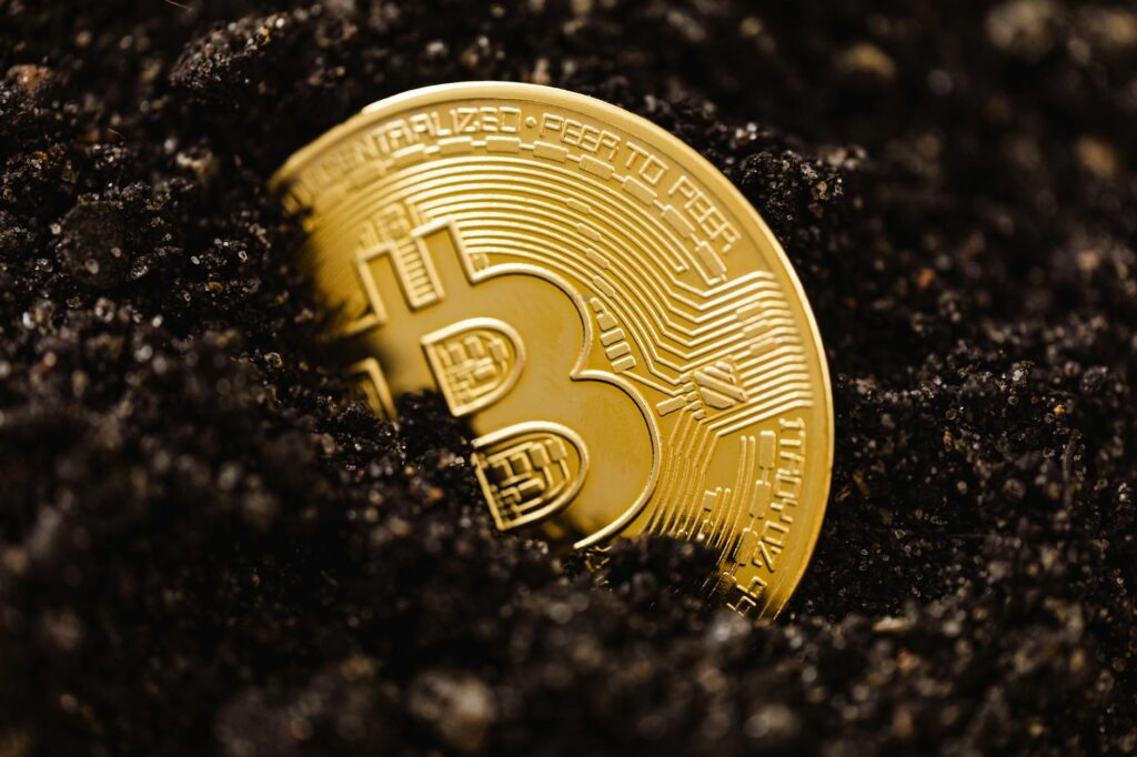 close up of a bitcoin coin lying in dirt on the ground